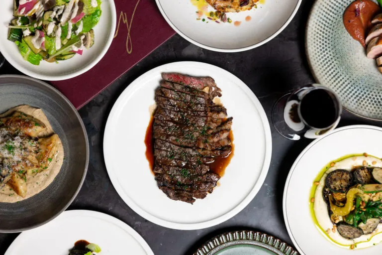 Overhead spread of grilled steak and side dishes at Pony Dining restaurant