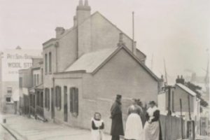 Historic stone building with colonial architecture and pedestrians in period dress, The Rocks.