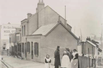 Historic stone building with colonial architecture and pedestrians in period dress, The Rocks.