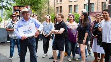 Tour guide leads group of visitors through historic Rocks street during walking tour.