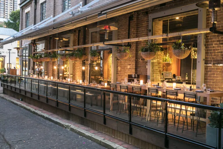 Modern restaurant with brick heritage building, outdoor seating, and hanging plants in The Rocks.