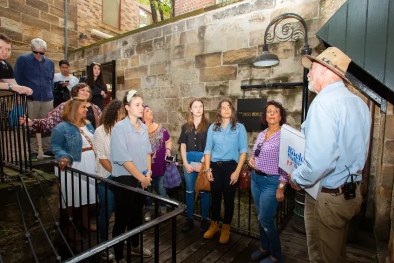 Guide leads Rocks Walking Tours group through historic sandstone building interior.