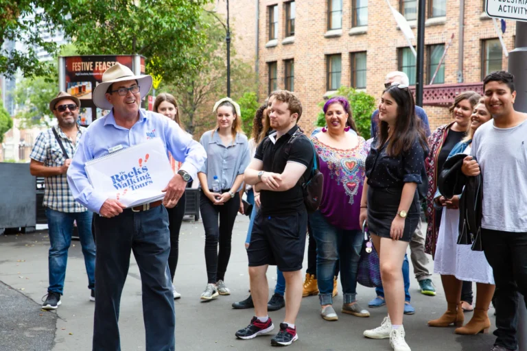 Rocks Walking Tours guide leading a diverse group through historic colonial buildings in The Rocks.