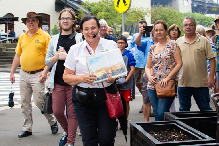 A smiling guide leads a walking tour group through the historic streets of The Rocks, Sydney