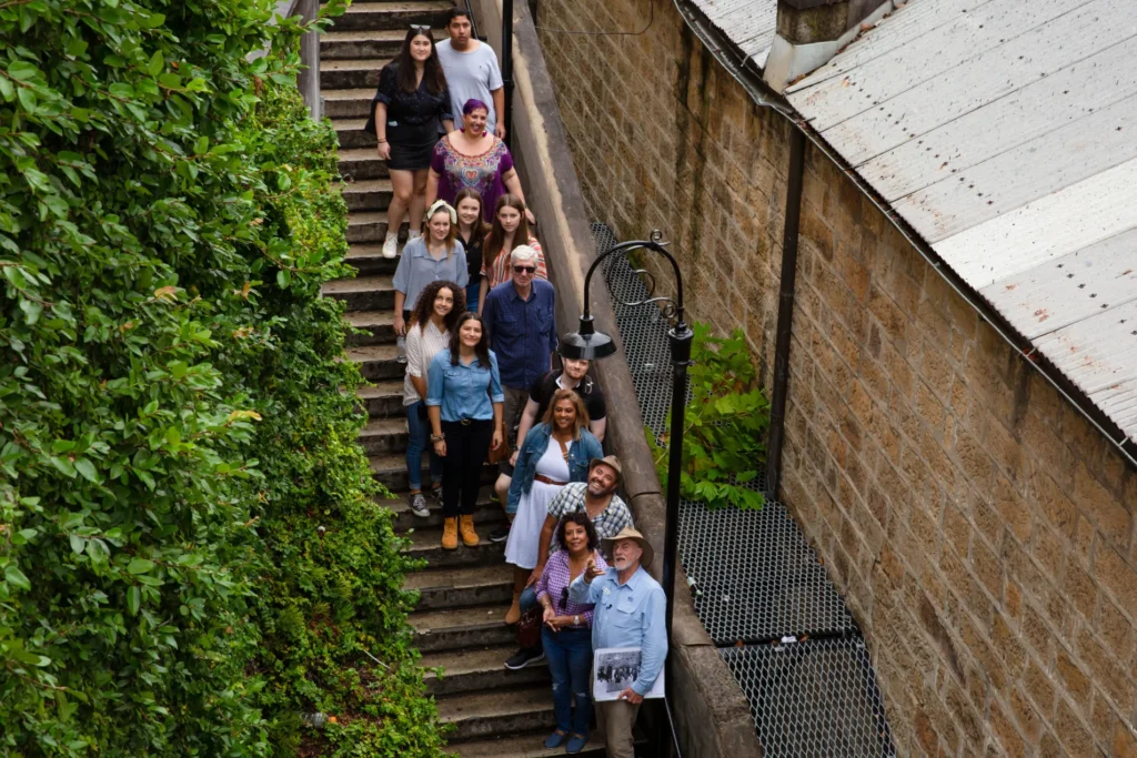 Group of walking tour participants descending historic stone steps between colonial buildings in The Rocks.