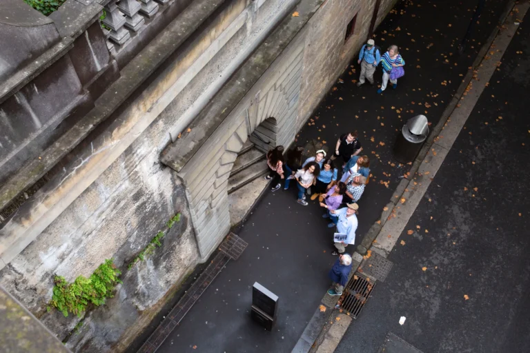 Guided walking tour group gathered in narrow Rocks laneway beside heritage stone walls.