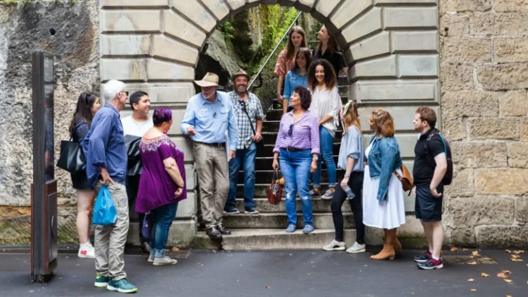 Guided walking tour group gathered at historic stone archway in The Rocks Sydney.