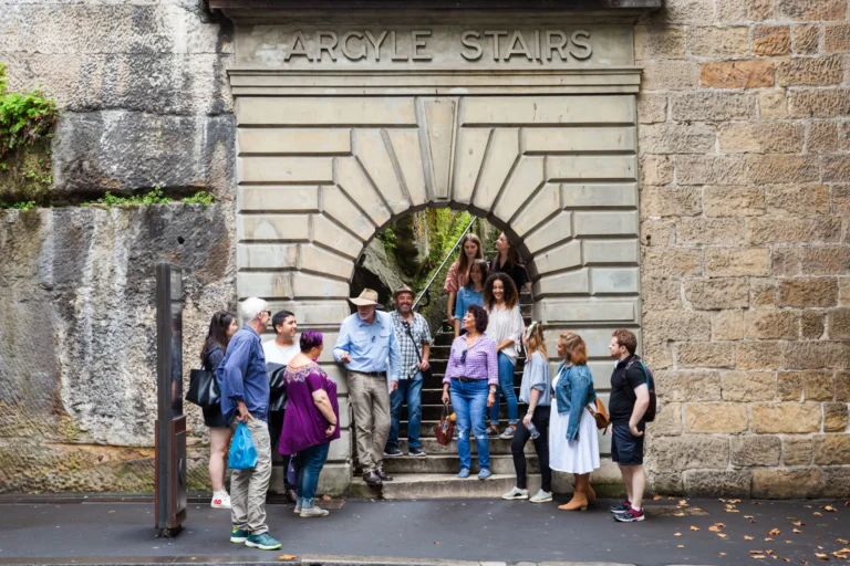 Walking tour group at Argyle Stairs archway in The Rocks heritage precinct, Sydney.